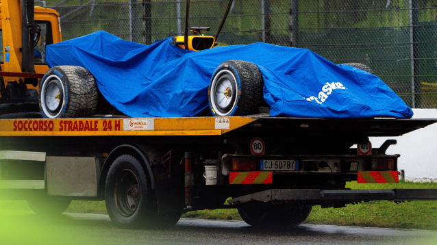 Racing Bulls' 2026 car under a blue sheet on a flat-bed truck at a rainy Imola