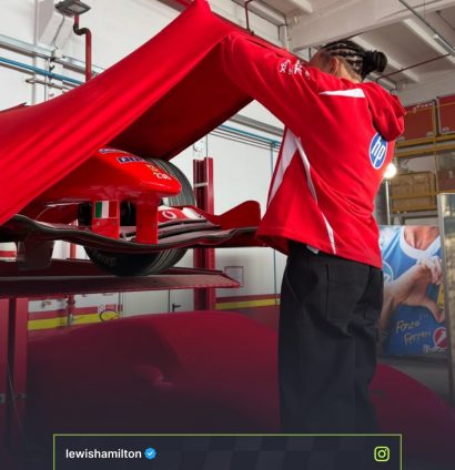 Lewis Hamilton lifts a red sheet with the nose and front wing of the Ferrari F2004 car visible