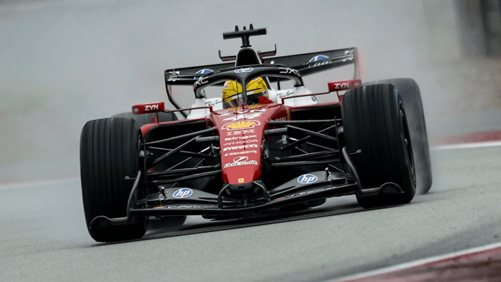 An action shot of Lewis Hamilton's Ferrari on track at a wet Barcelona with spray in the background