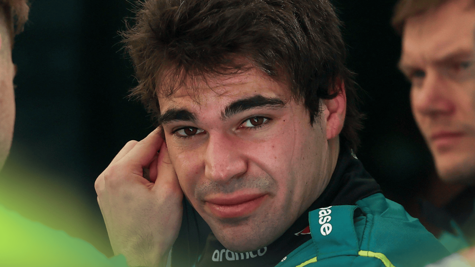 Lance Stroll eyes the camera as he adjusts his earplugs in the Aston Martin garage