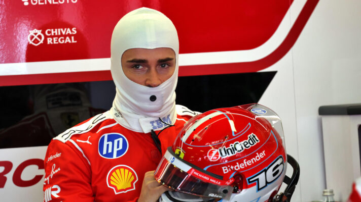 Charles Leclerc holding his helmet in the Ferrari garage
