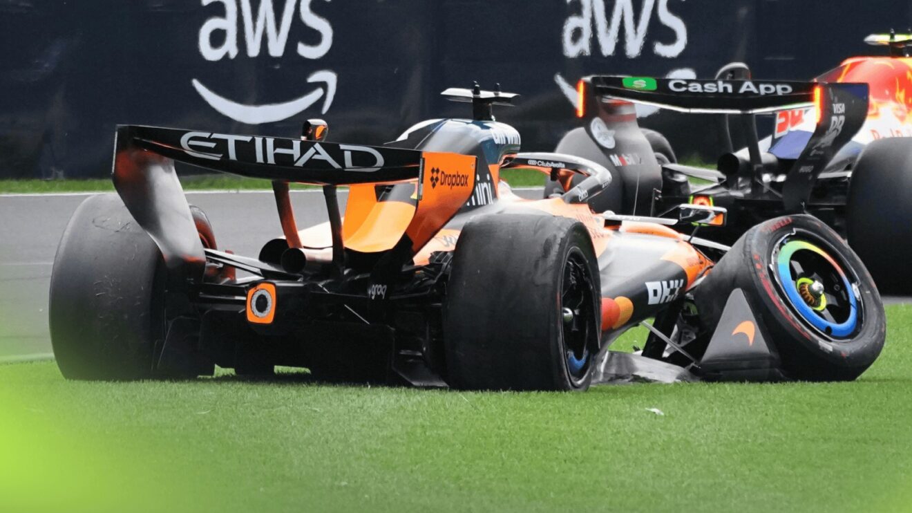A rear-view shot of Oscar Piastri's McLaren on the grass with severe damage