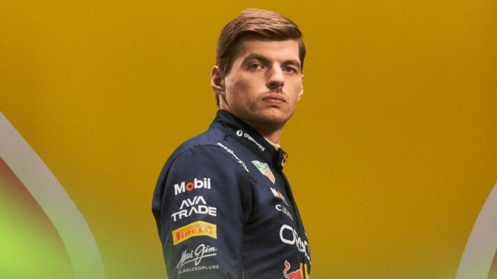 A studio shot of Max Verstappen in Red Bull 2026 overalls against a yellow background