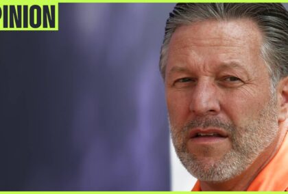 Zak Brown looks on as he makes his way through the paddock with an 'opinion' tab in the top-left corner