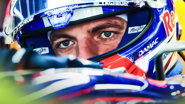 Max Verstappen's eyes visible through the open visor of his helmet as he sits in the Red Bull RB22