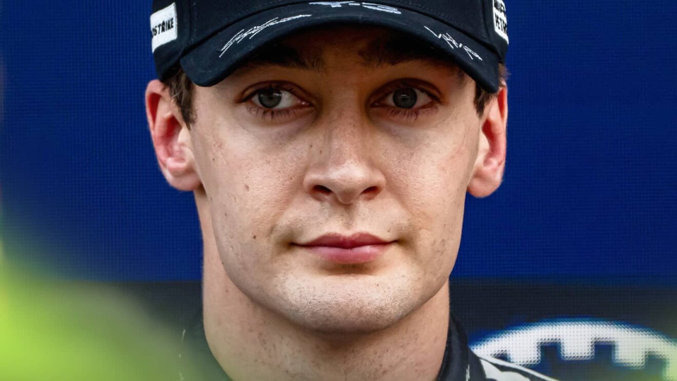 A close-up shot of George Russell wearing a Mercedes cap