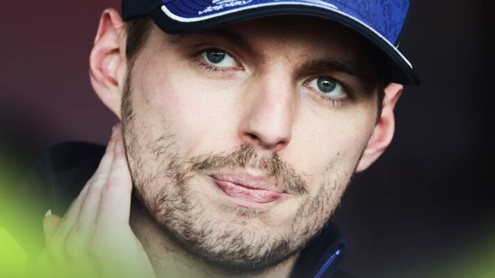 A close-up shot of Max Verstappen holding his hand to his neck as he speaks to the media