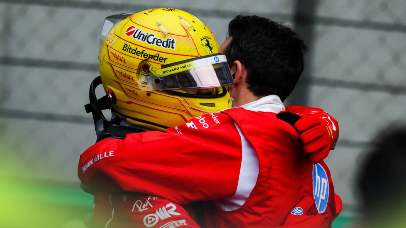 Lewis Hamilton embraces a Ferrari mechanic while wearing his helmet