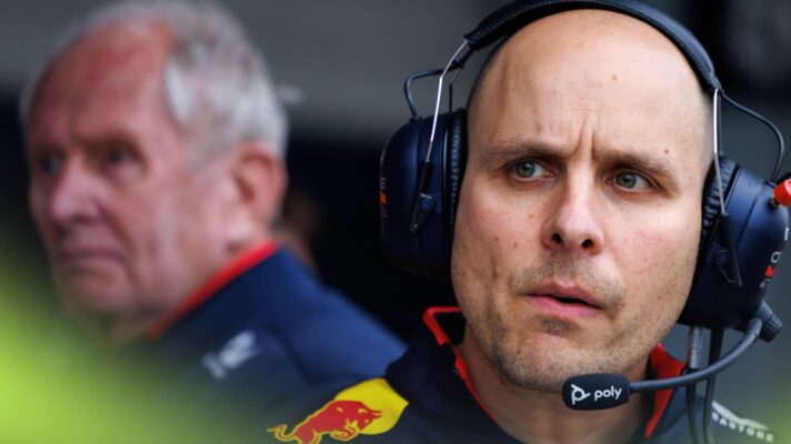 GianPiero Lambiase looks on while wearing a set of headphones with Helmut Marko in the background