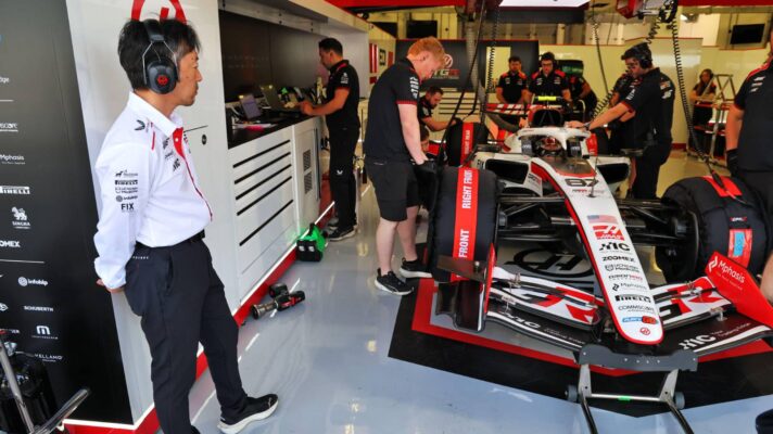 Haas team principal Ayao Komatsu looks into the team garage where Esteban Ocon's VF-26 is being prepared by mechanics.