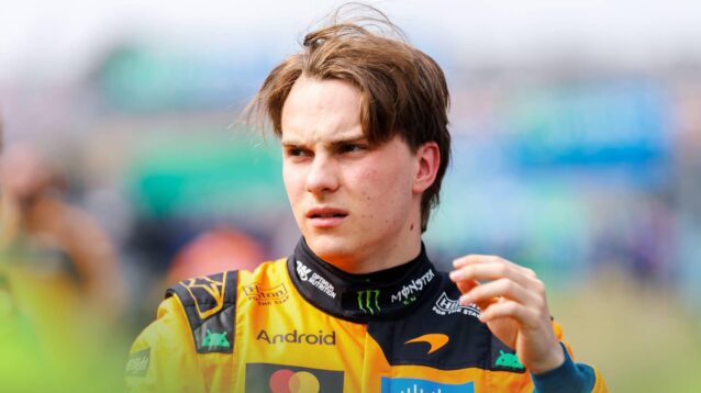 Oscar Piastri looks on with his left arm raised on the grid at Suzuka