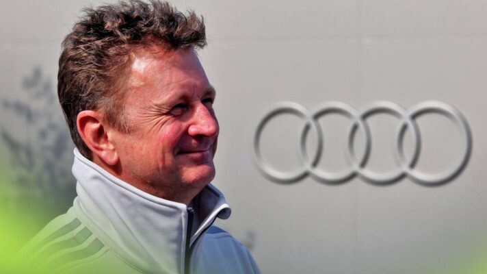 Audi stalwart Allan McNish with the 'Four Rings' logo in the background.