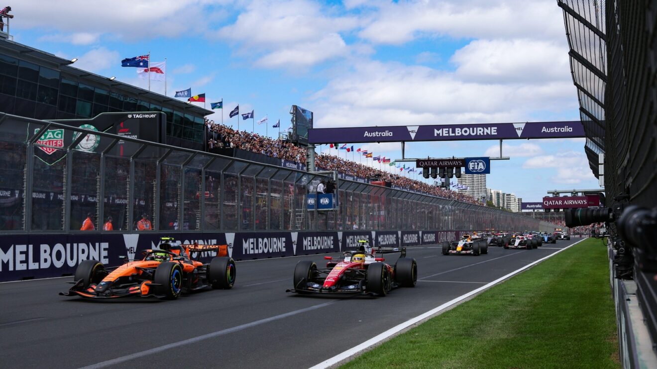The start of the Australian Grand Prix sees cars race away from the line, taken from a low angle on the front straight as a McLaren and Ferrari head to the left of the shot.