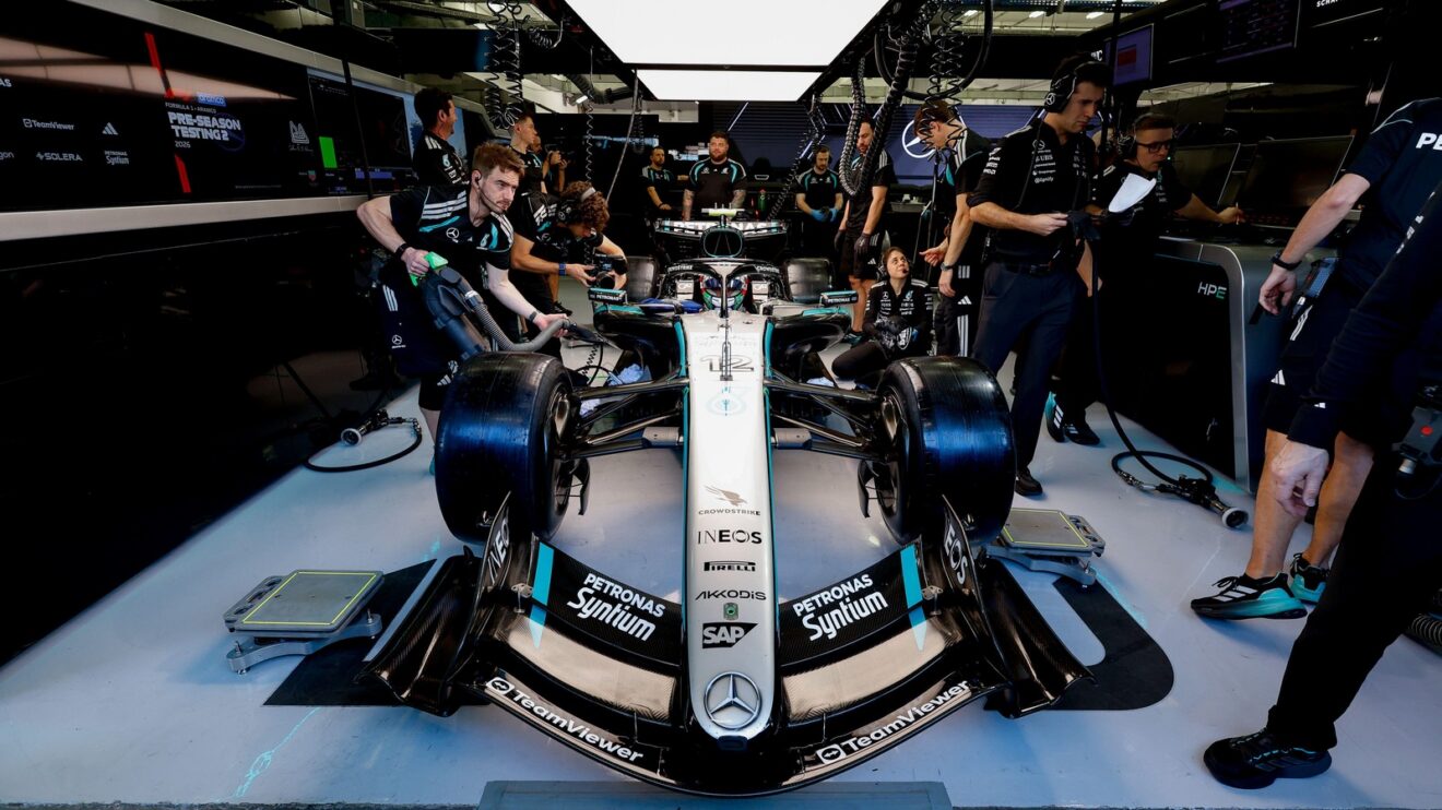Kimi Antonelli sits in his Mercedes W17 in the team garage as mechanics work around him.
