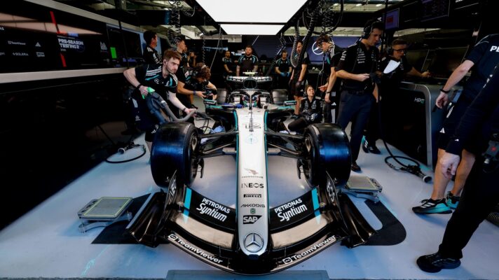 Kimi Antonelli sits in his Mercedes W17 in the team garage as mechanics work around him.