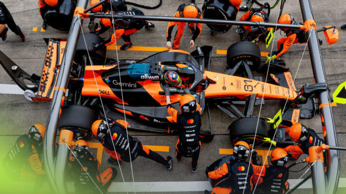 An overhead shot as Oscar Piastri pits, with his McLaren surrounded by mechanics.