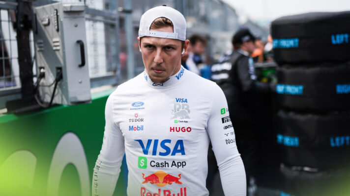 A serious looking Liam Lawson walks down the grid ahead of a grand prix.