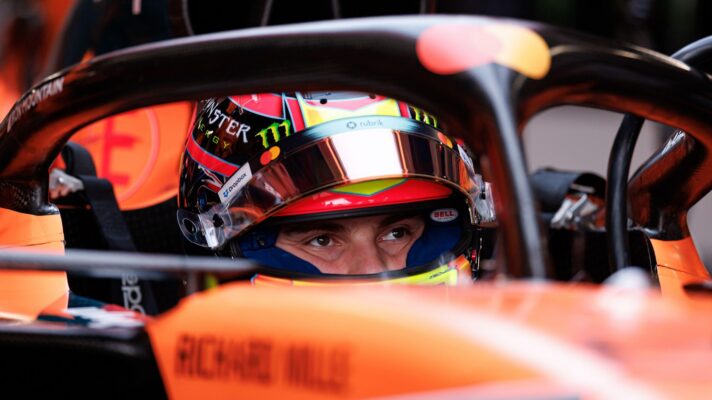 Oscar Piastri sits in the cockpit of his McLaren with his visor up.