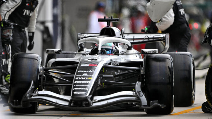 Valtteri Bottas leaves his Cadillac pit stop, mechanics stepping back from the car