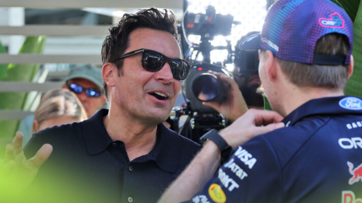 Jimmy Fallon in sun glasses speaks while speaking with Max Verstappen in the Miami GP paddock.