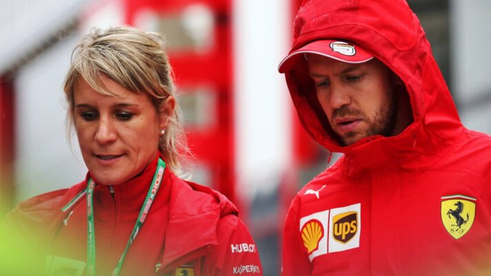 Britta Roeske and a hooded Sebastian Vettel in conversation as they walk in the F1 paddock