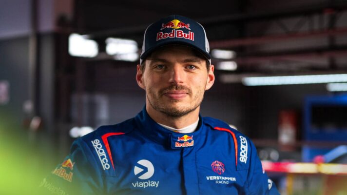 Max Verstappen eyes the camera while wearing Team Verstappen overalls and a Red Bull cap