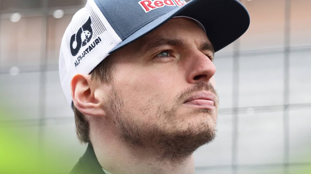 A close up shot of Max Verstappen looking into the distance while wearing a Red Bull cap