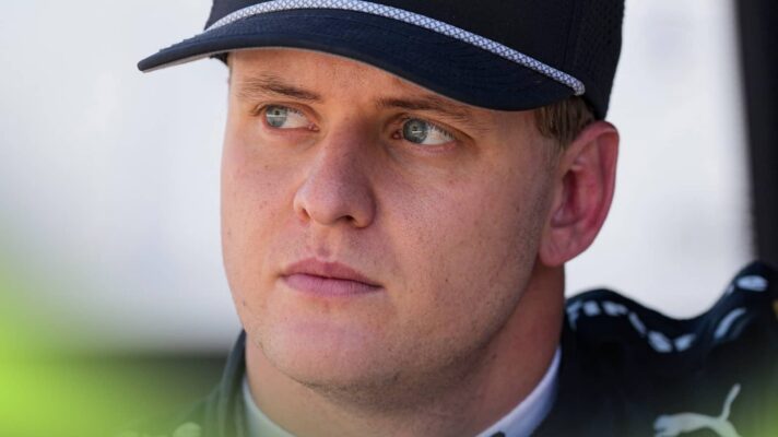 A close-up shot of Mick Schumacher wearing a black cap and race suit