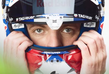 A close-up shot of Max Verstappen holding on to his helmet with his visor open
