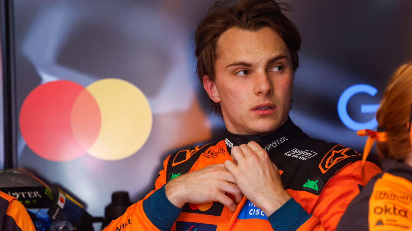 Oscar Piastri looking to the side in the McLaren garage while doing up his race suit