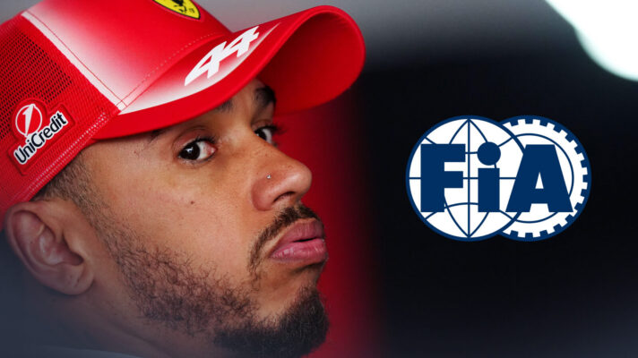 Lewis Hamilton wearing a Ferrari cap and looking side-eyed towards the camera, the FIA logo