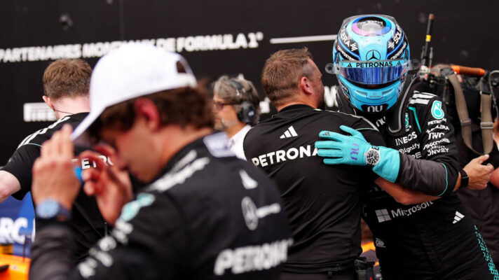 George Russell celebrates while blurred Kimi Antonelli in the foreground walks off