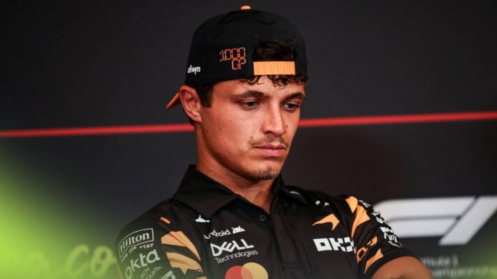 Lando Norris looks towards the floor in a press conference