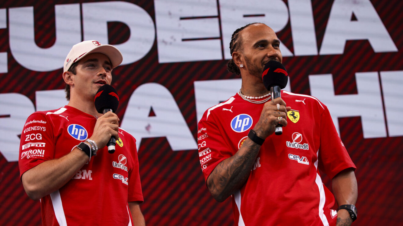 Charles Leclerc and Lewis Hamilton holding mics on a fan stage with Ferrari's name in the background
