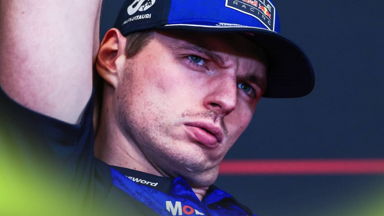 A close-up shot of Max Verstappen with his head tilted in a press conference