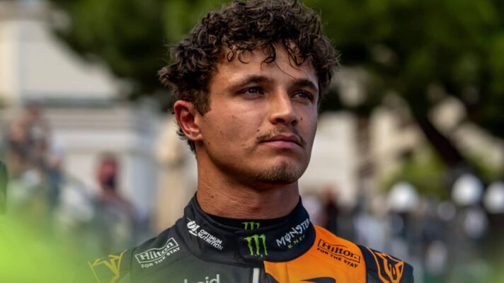 Lando Norris stood wearing black-and-orange McLaren overalls on the grid in Monaco