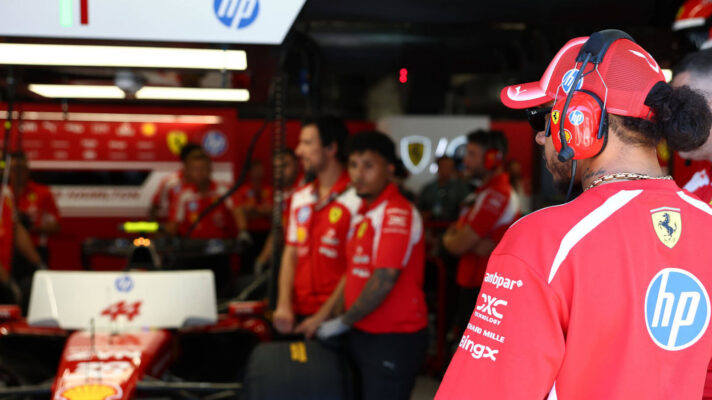 Lewis Hamilton looking at his no 44 Ferrari SF-26 in the Ferrari garage, mechanics around the car