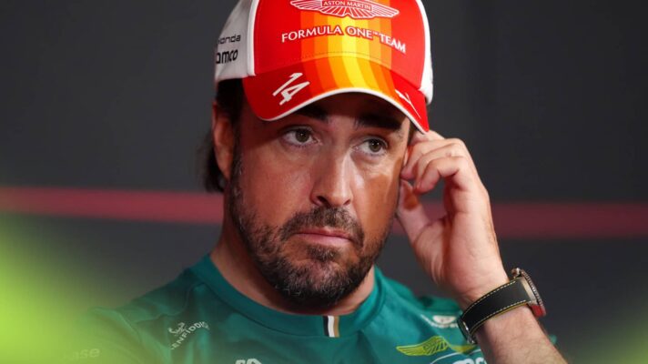 Fernando Alonso holds his hand to his face in a press conference