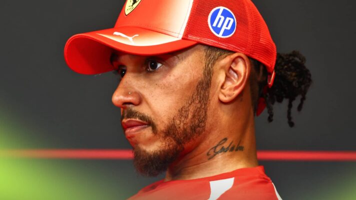A side-profile shot of Lewis Hamilton sitting in a press conference