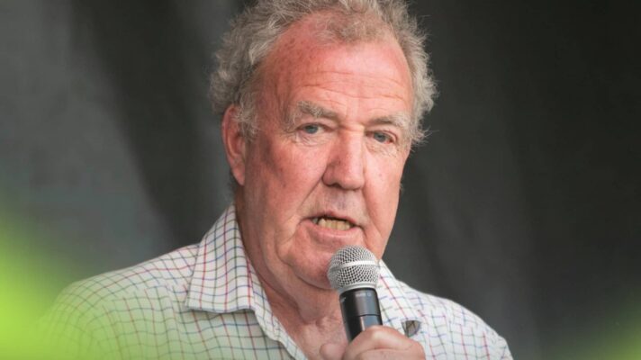 Jeremy Clarkson speaking on stage while holding a microphone to his mouth