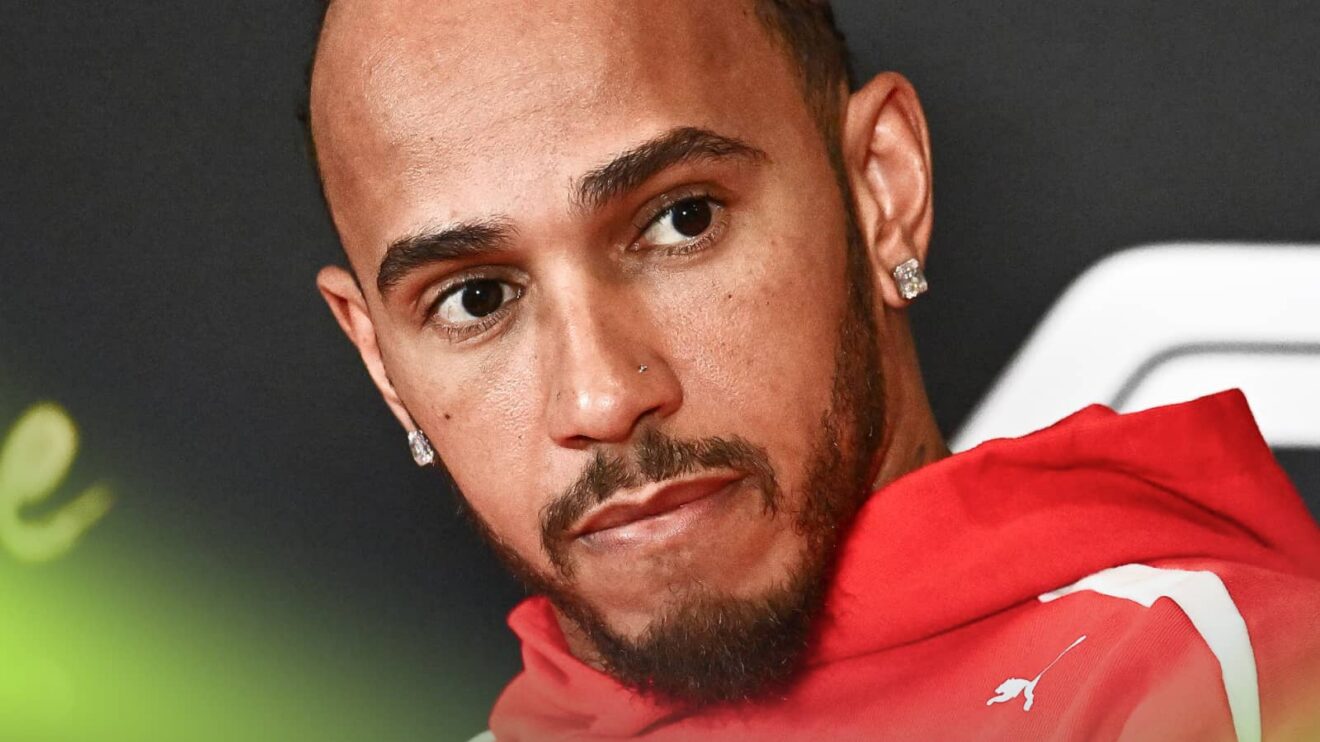 A close-up shot of Lewis Hamilton looking tense in a press conference