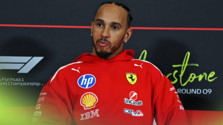 Lewis Hamilton looks on in a press conference while wearing a red Ferrari hoodie