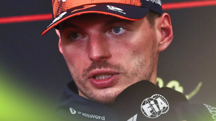 A close-up shot of Max Verstappen speaking in a press conference while holding a microphone