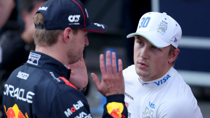 Max Verstappen with his hands raised speaking with Liam Lawson