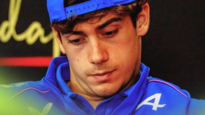A close-up shot of Franco Colapinto looking down in a press conference