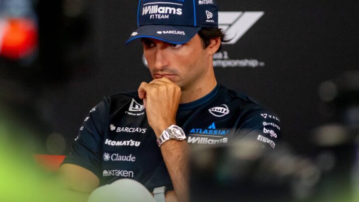 Carlos Sainz holds his hand to his chin in a press conference