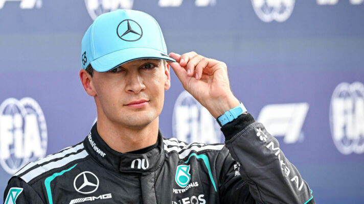 George Russell touches his Mercedes cap during an interview