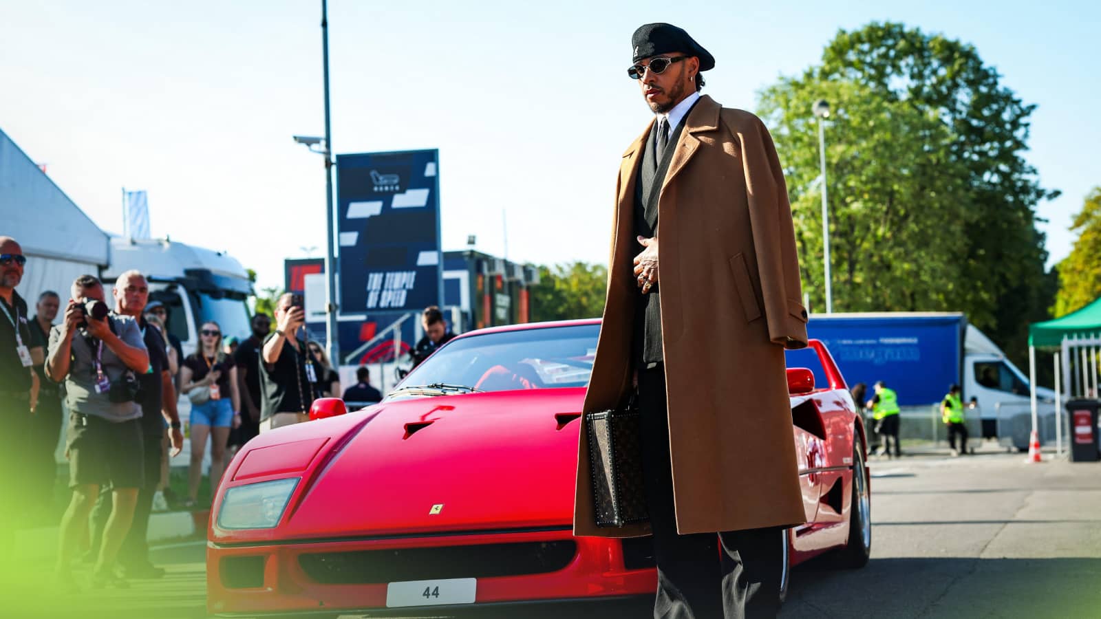 Lewis Hamilton poses in an overcoat and beret alongside a Ferrari F40 as he arrives at Monza
