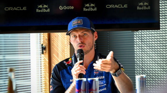 Max Verstappen gestures as he speaks to the media with a mic in hand