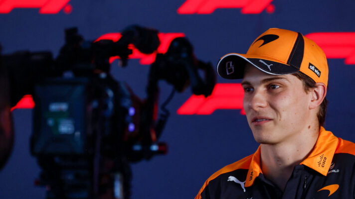 Oscar Piastri looking at the camera as he is interviewed, wearing a McLaren cap